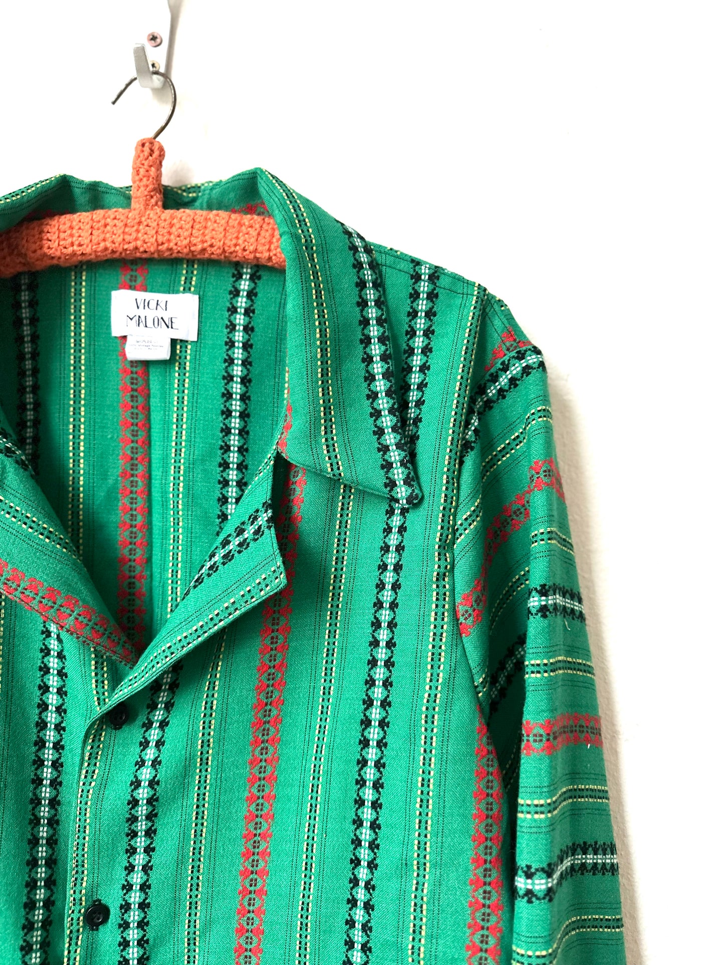 Green patterned shirt on a hanger with a visible brand tag.