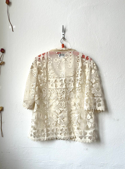 Cream lace top hanging on a white wall