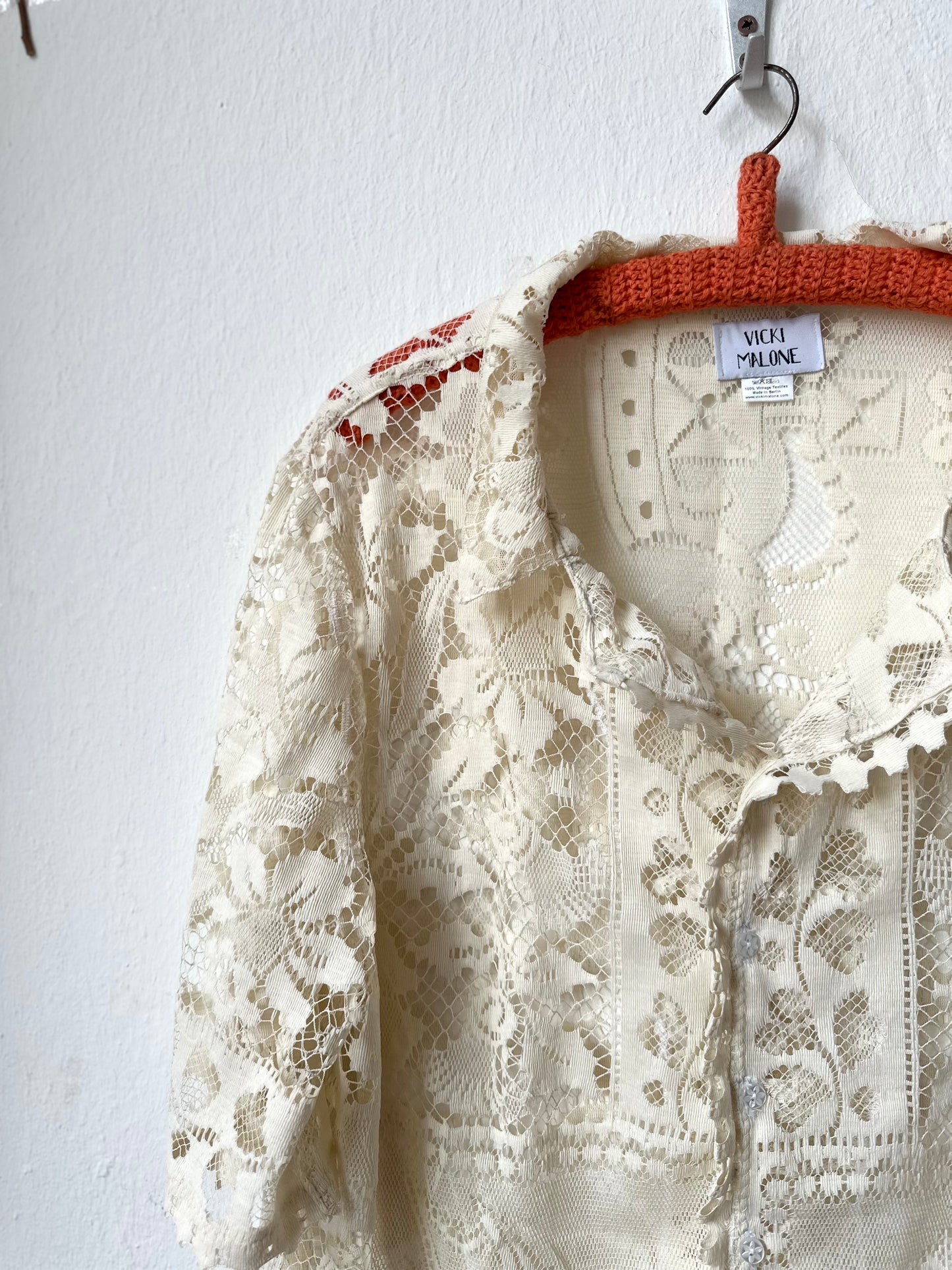 Cream lace garment on a hanger against a white background