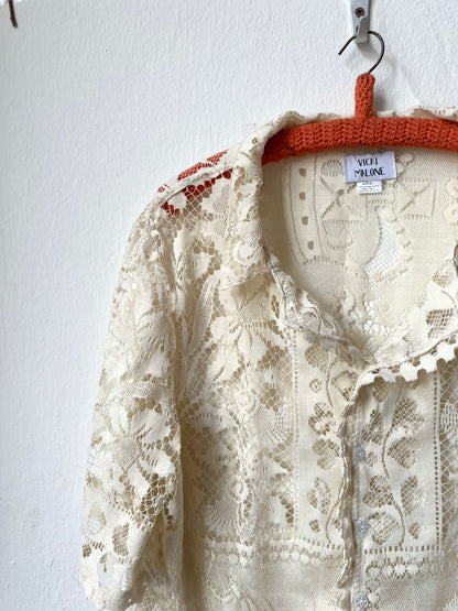 Cream lace garment on a hanger against a white background