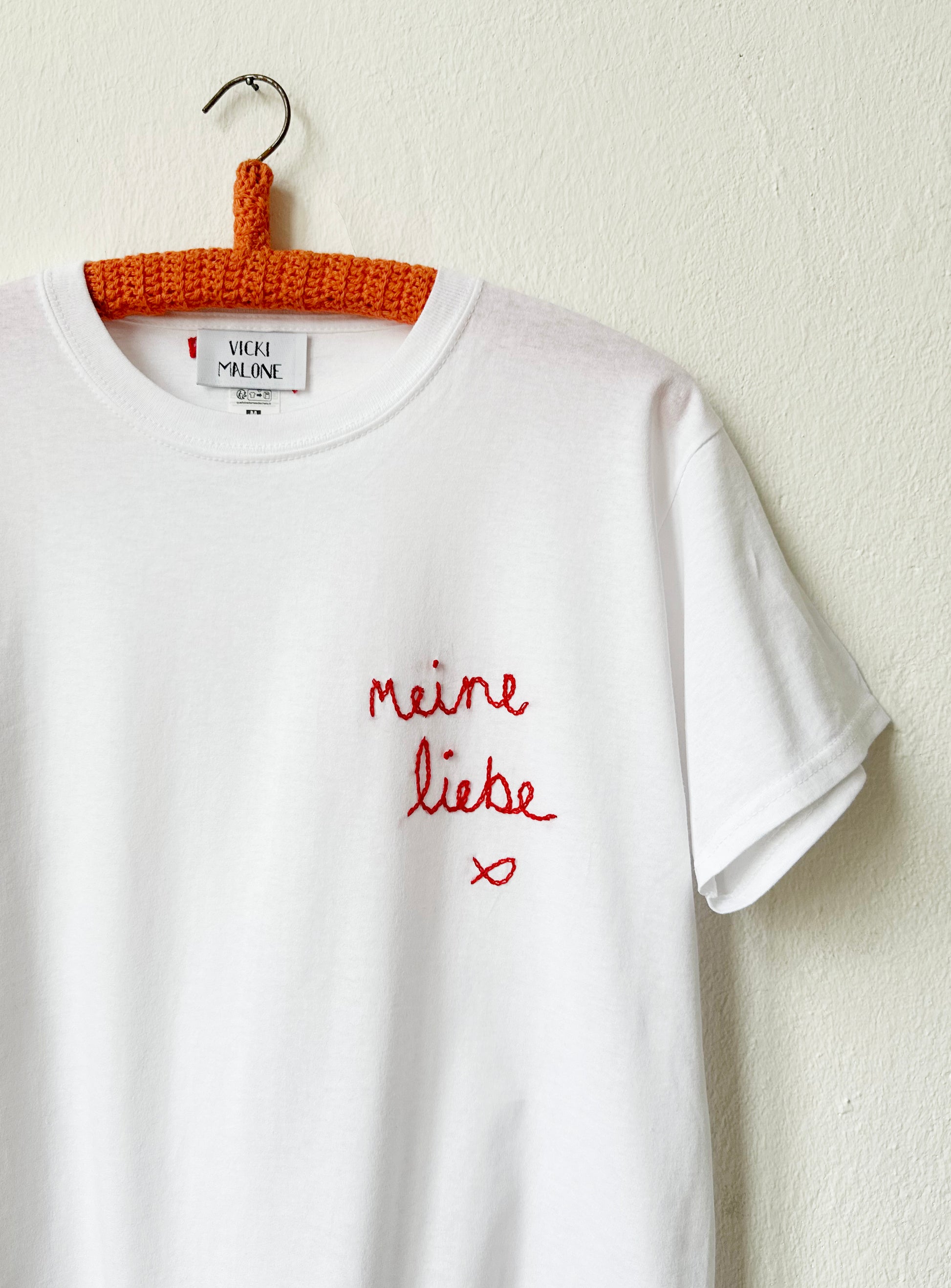 Detailed look at the red embroidery on the white tee
