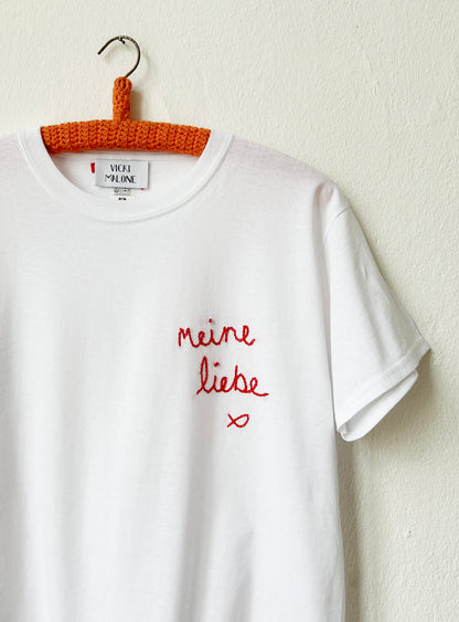 Detailed look at the red embroidery on the white tee

