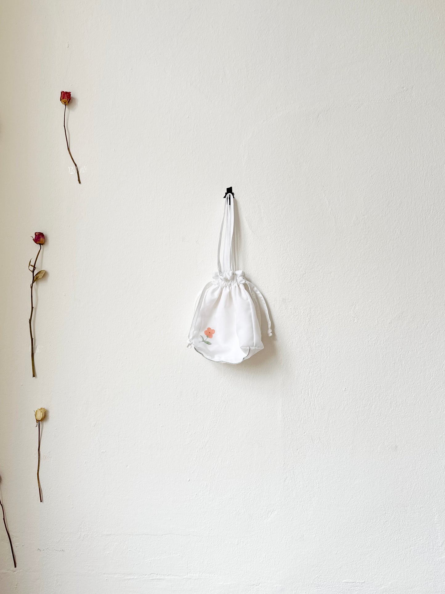 A evening bag with drawcord hangs on a wall