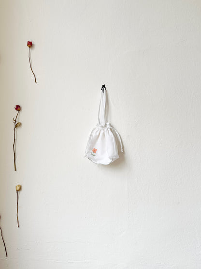 A evening bag with drawcord hangs on a wall