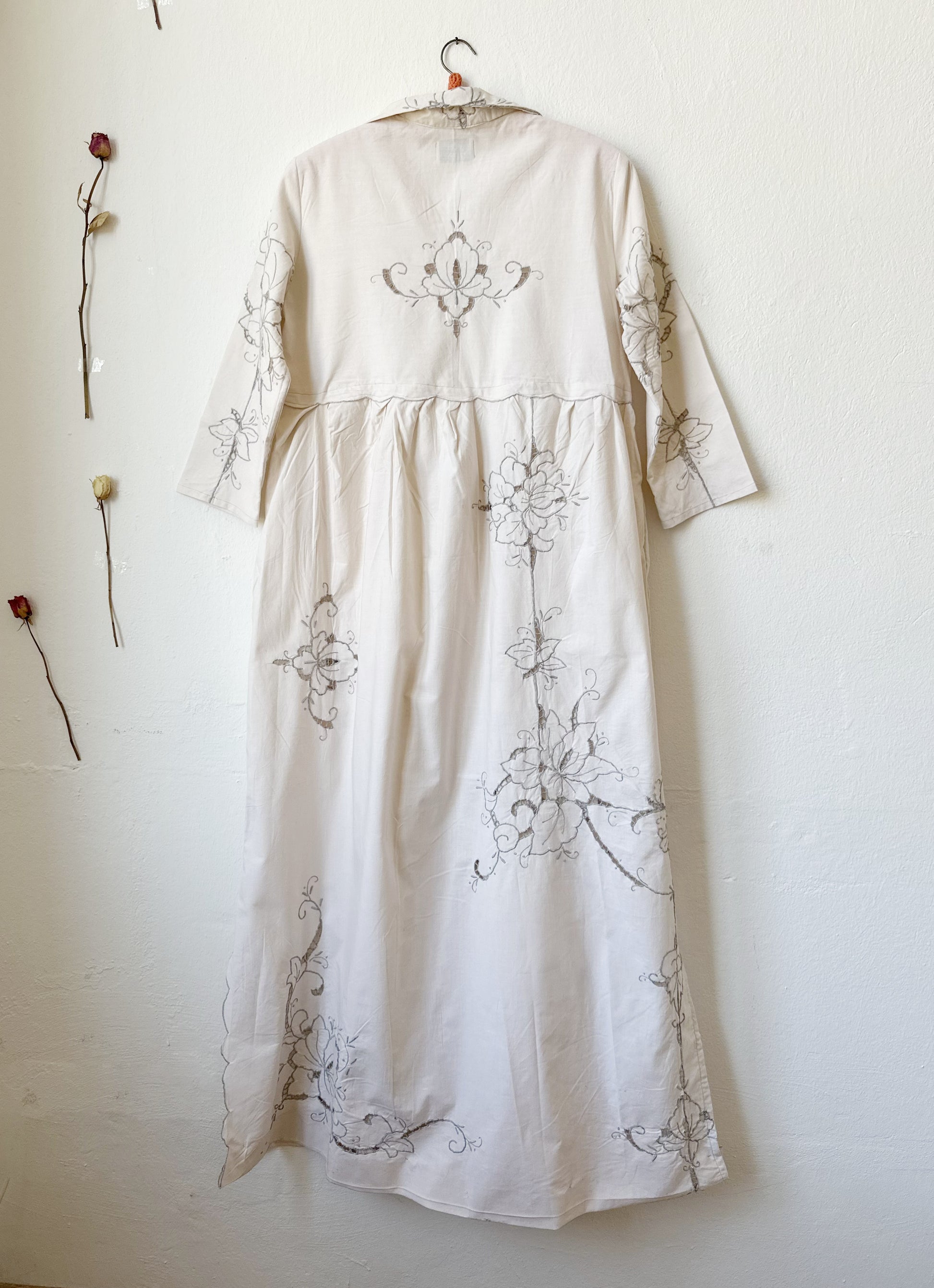 The back view of a maxi length grey embroidered dress.