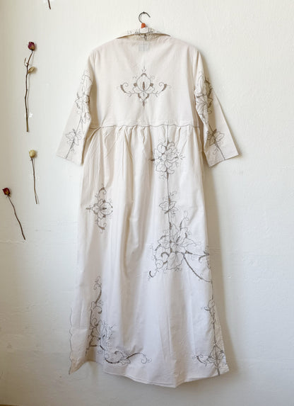 The back view of a maxi length grey embroidered dress.