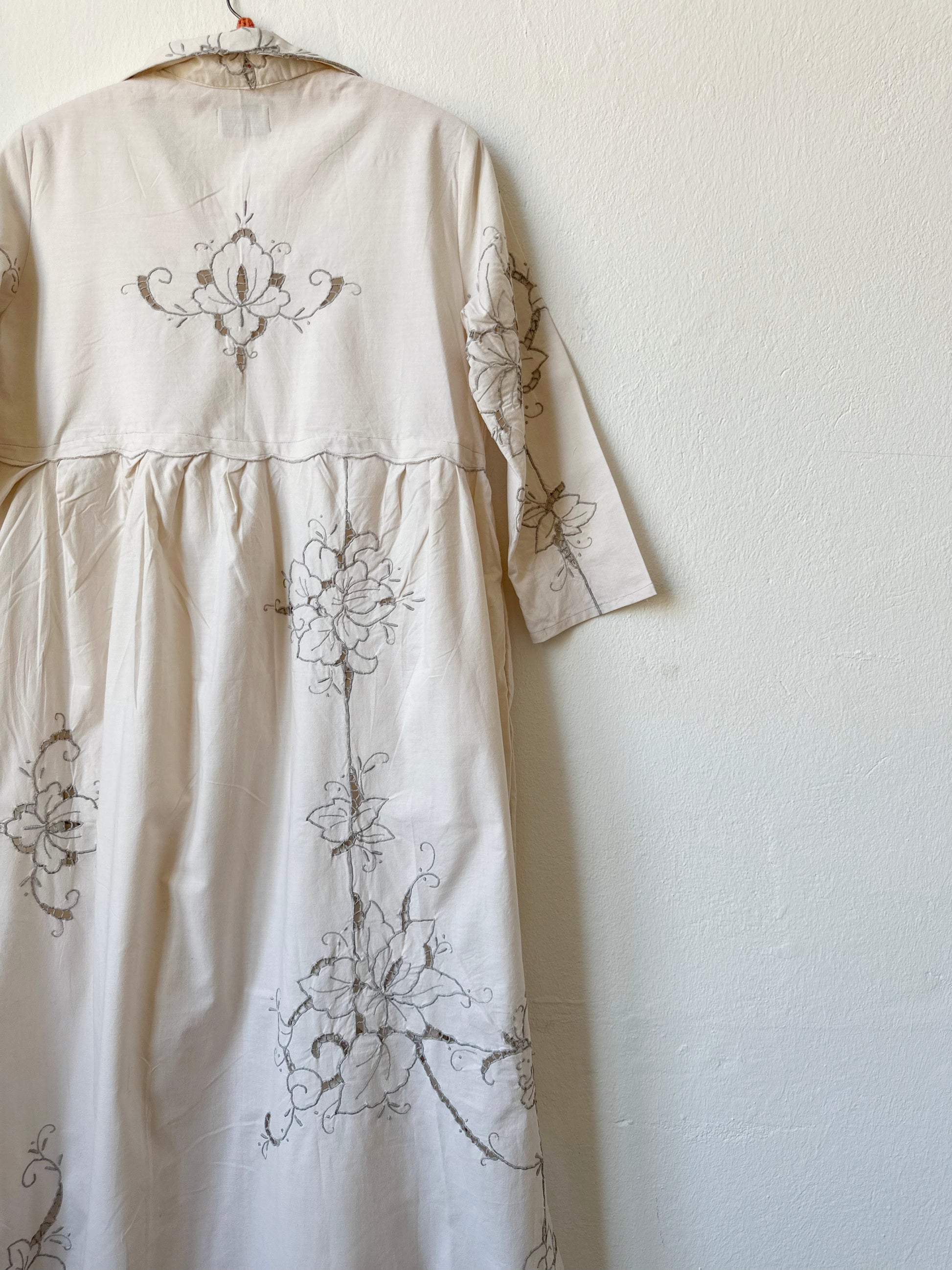A detailed back view of a maxi length grey embroidered dress.