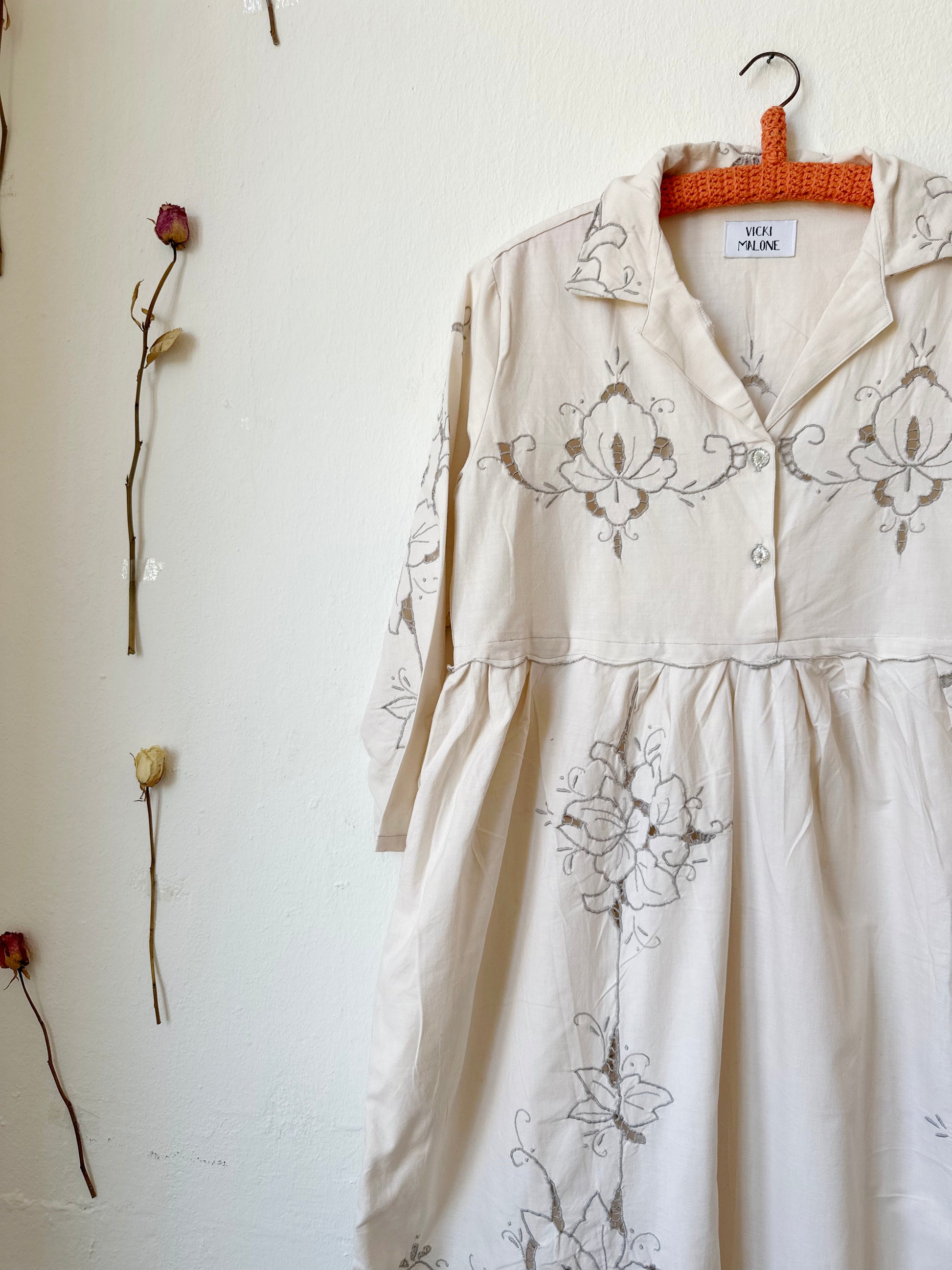 A front detailed view of a maxi length grey embroidered dress.