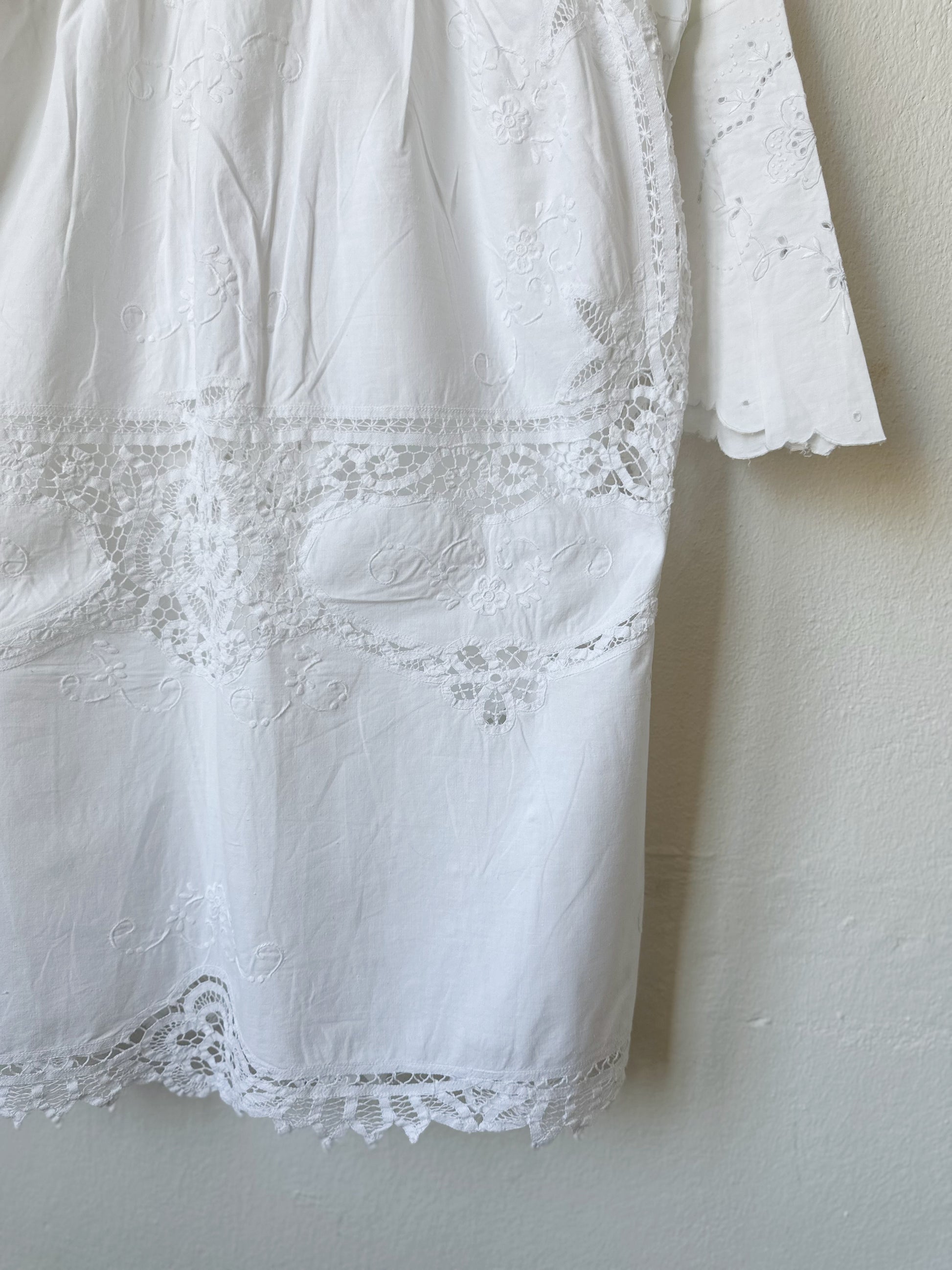 A detailed view of the back of a white lace dress hanging on a wall.