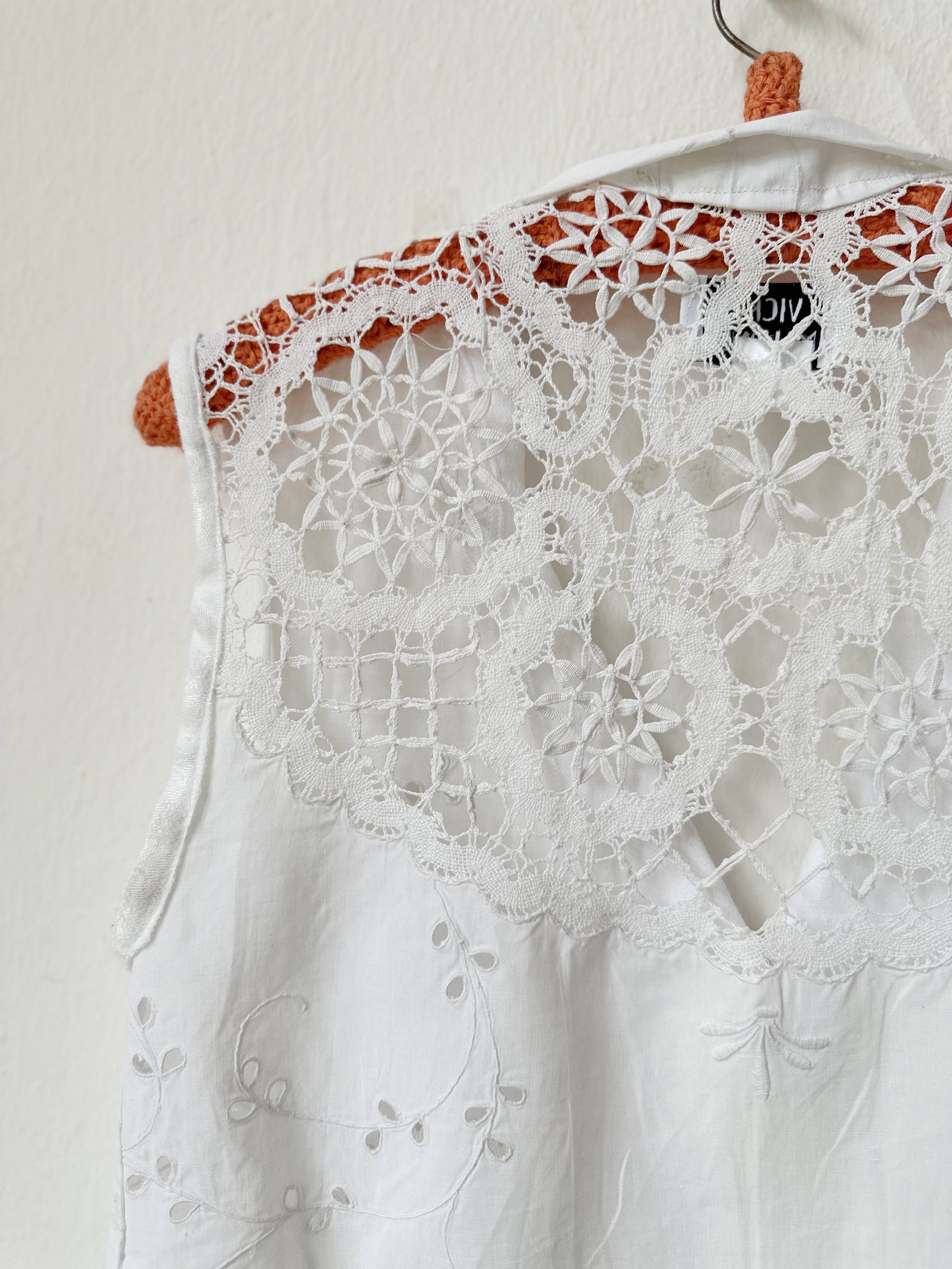 White lace top on a hanger against a plain background