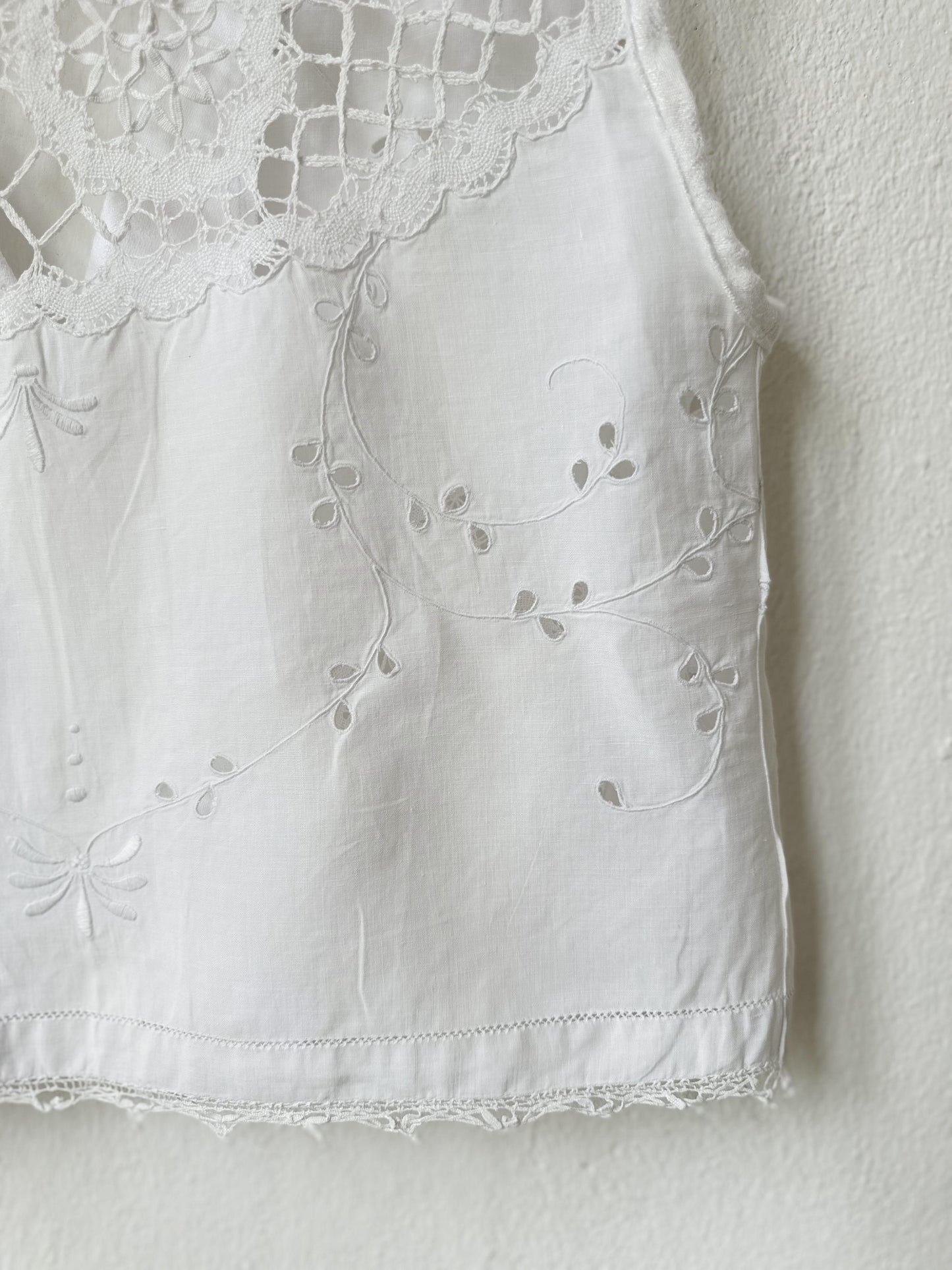 White sleeveless top with lace detailing on a plain background