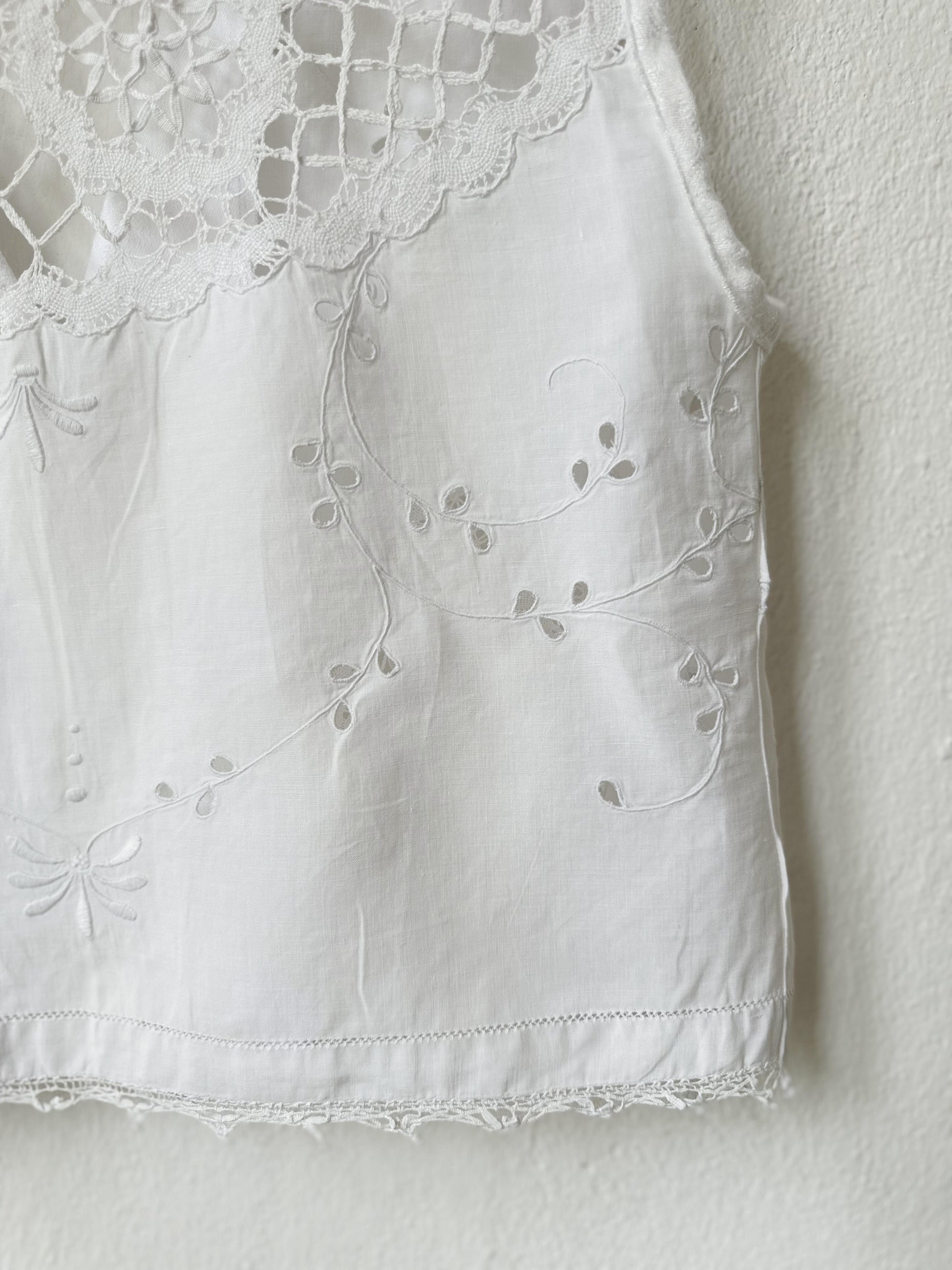White sleeveless top with lace detailing on a plain background