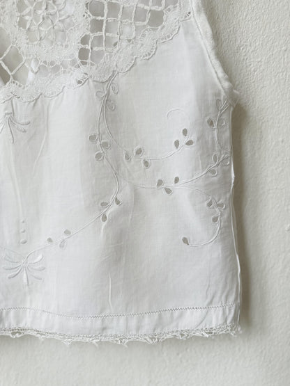 White sleeveless top with lace detailing on a plain background