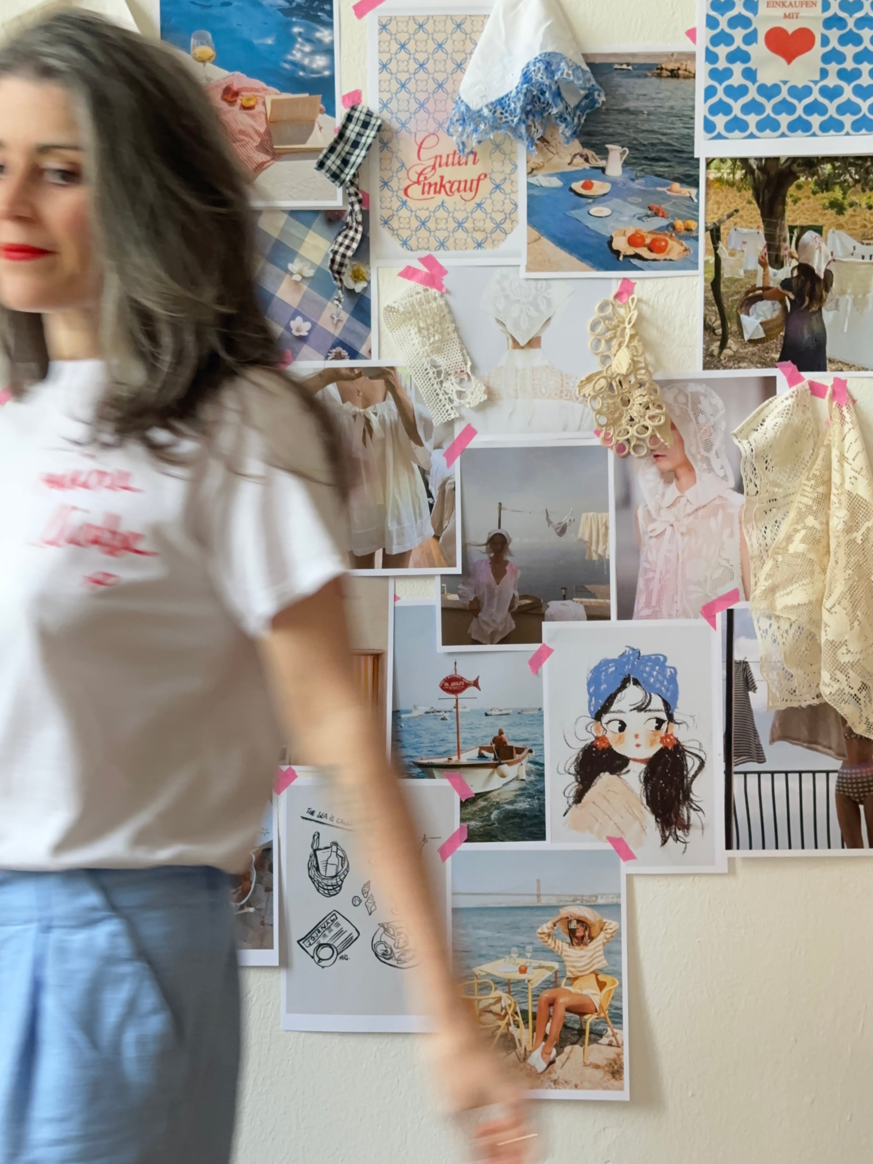 Woman walking past a wall with various photos and decorations