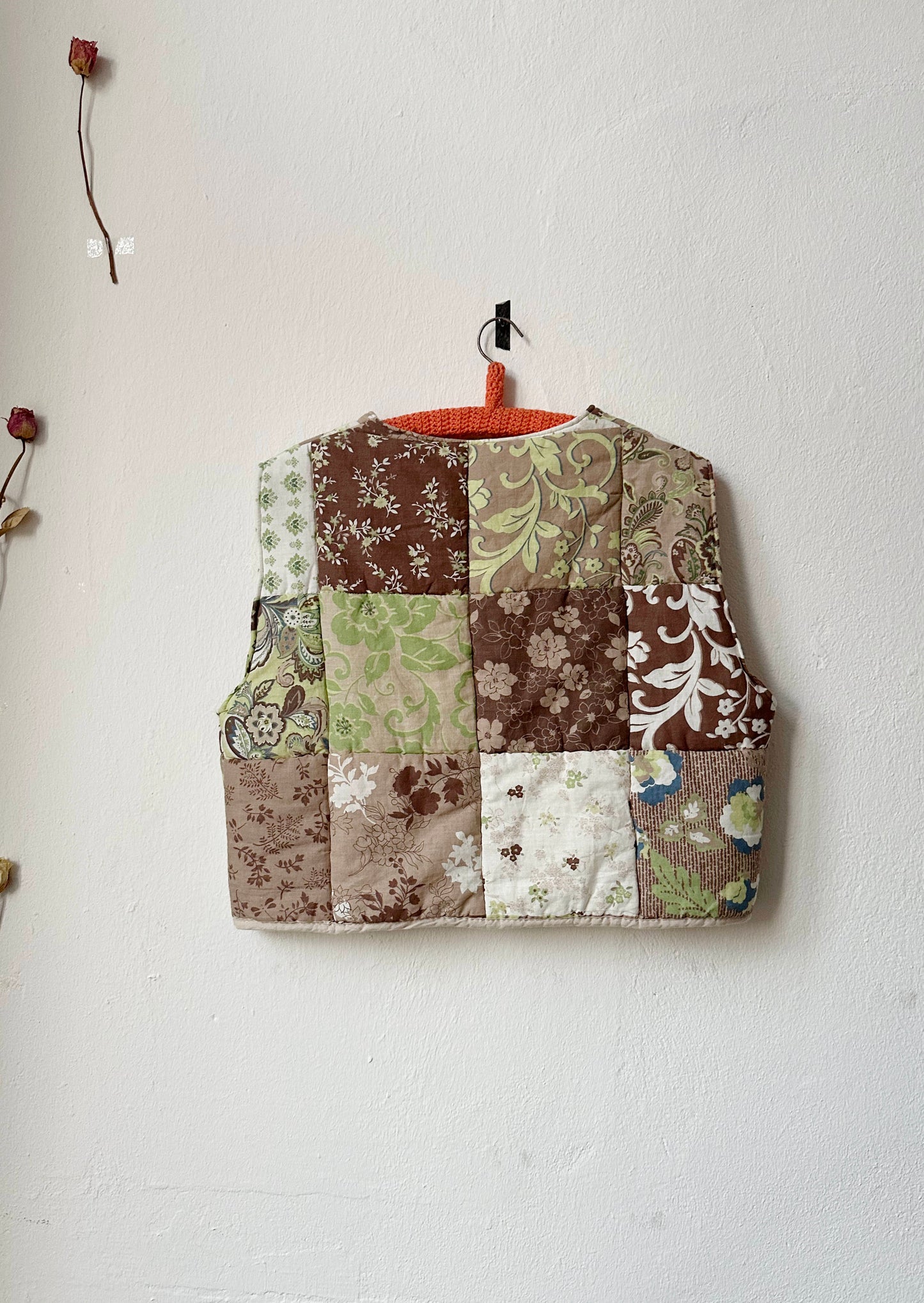 Back view of brown and green patterned quilt vest.