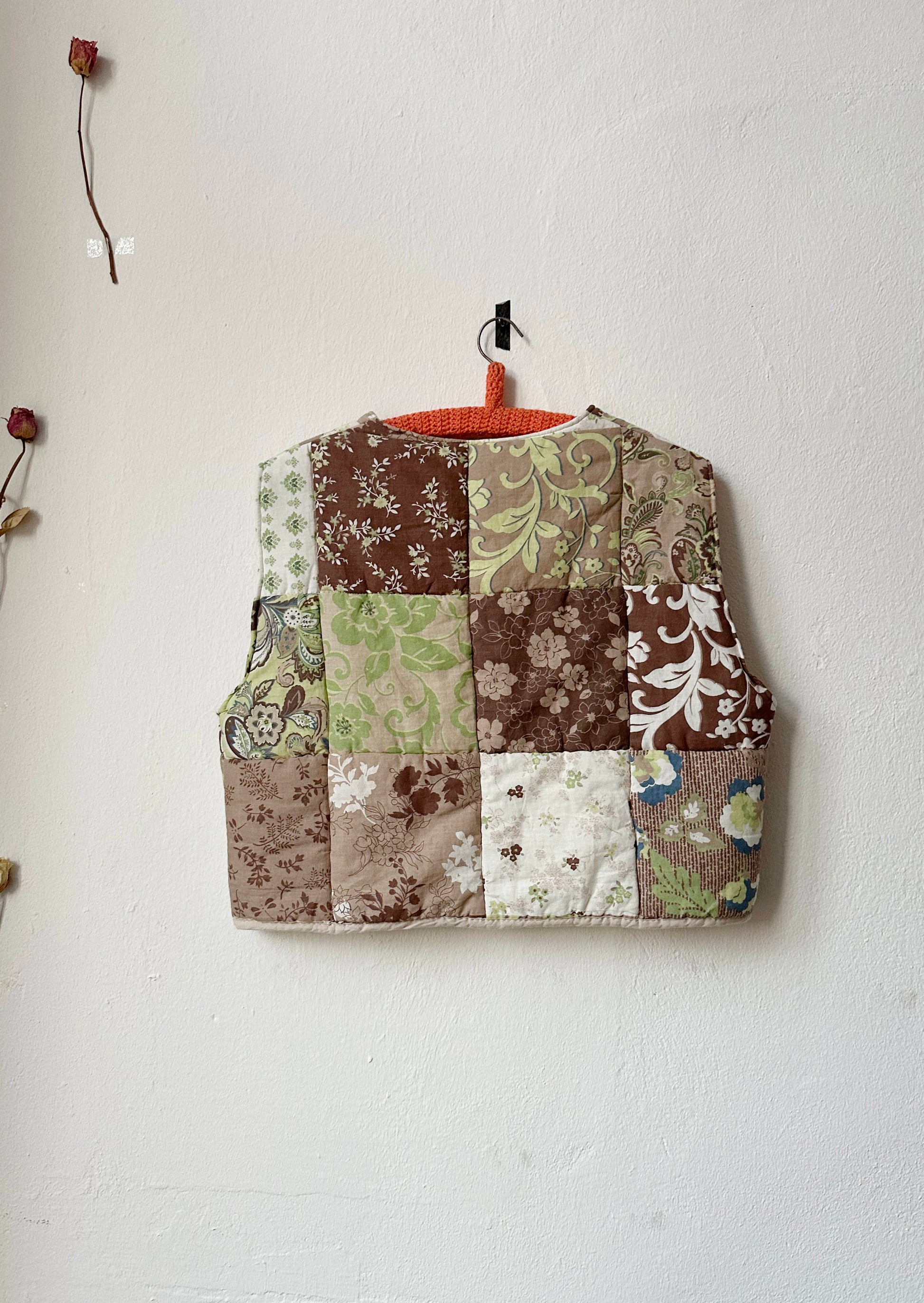 Back view of brown and green patterned quilt vest.