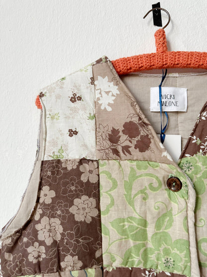 Front detail view of a brown and green patterned quilt vest with buttons.