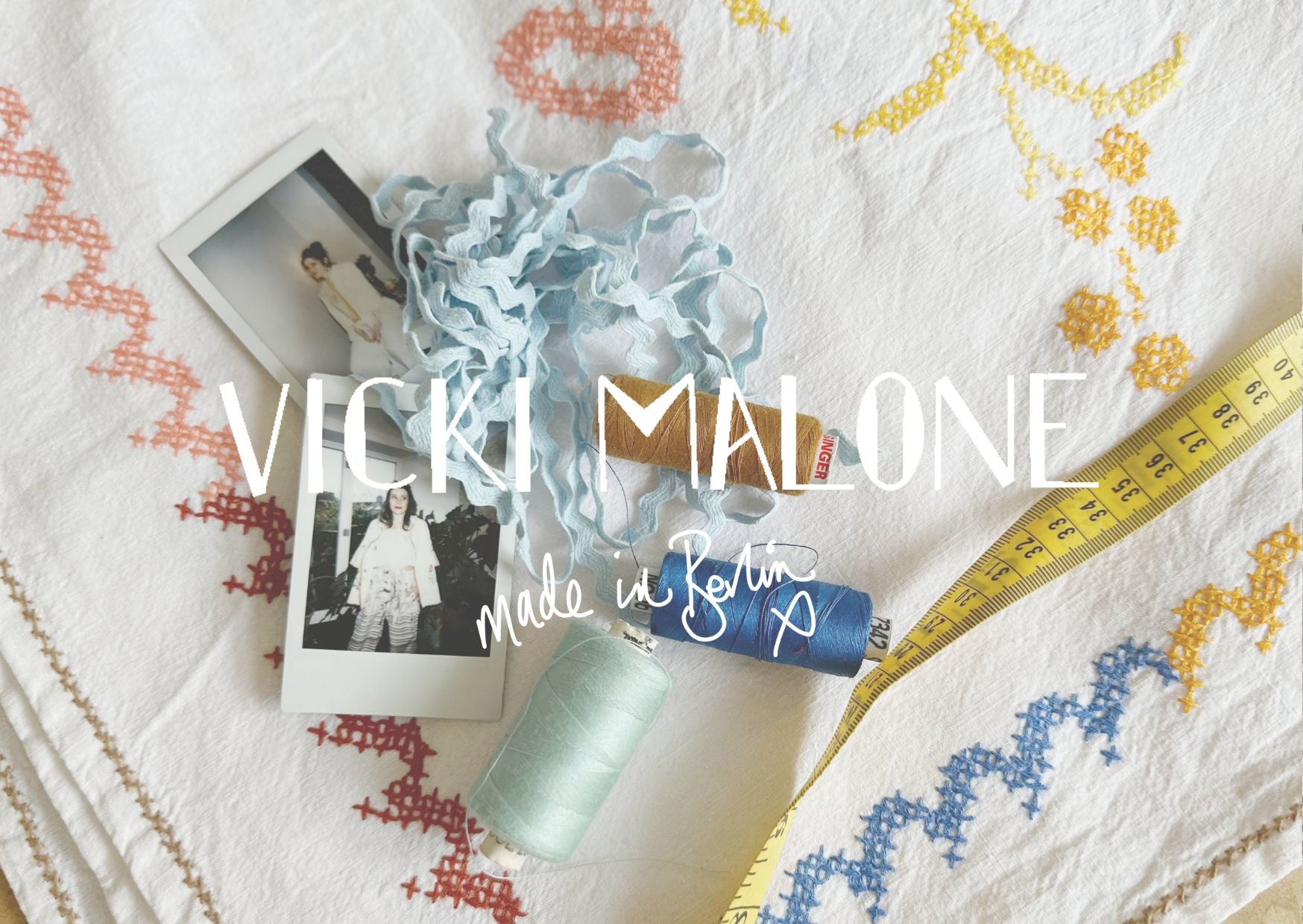 Text 'Vicki Malone Made in Berlin' with fabric, photos, and measuring tape on a patterned background