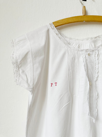 Vintage white dress with lace details on a hanger against a white background