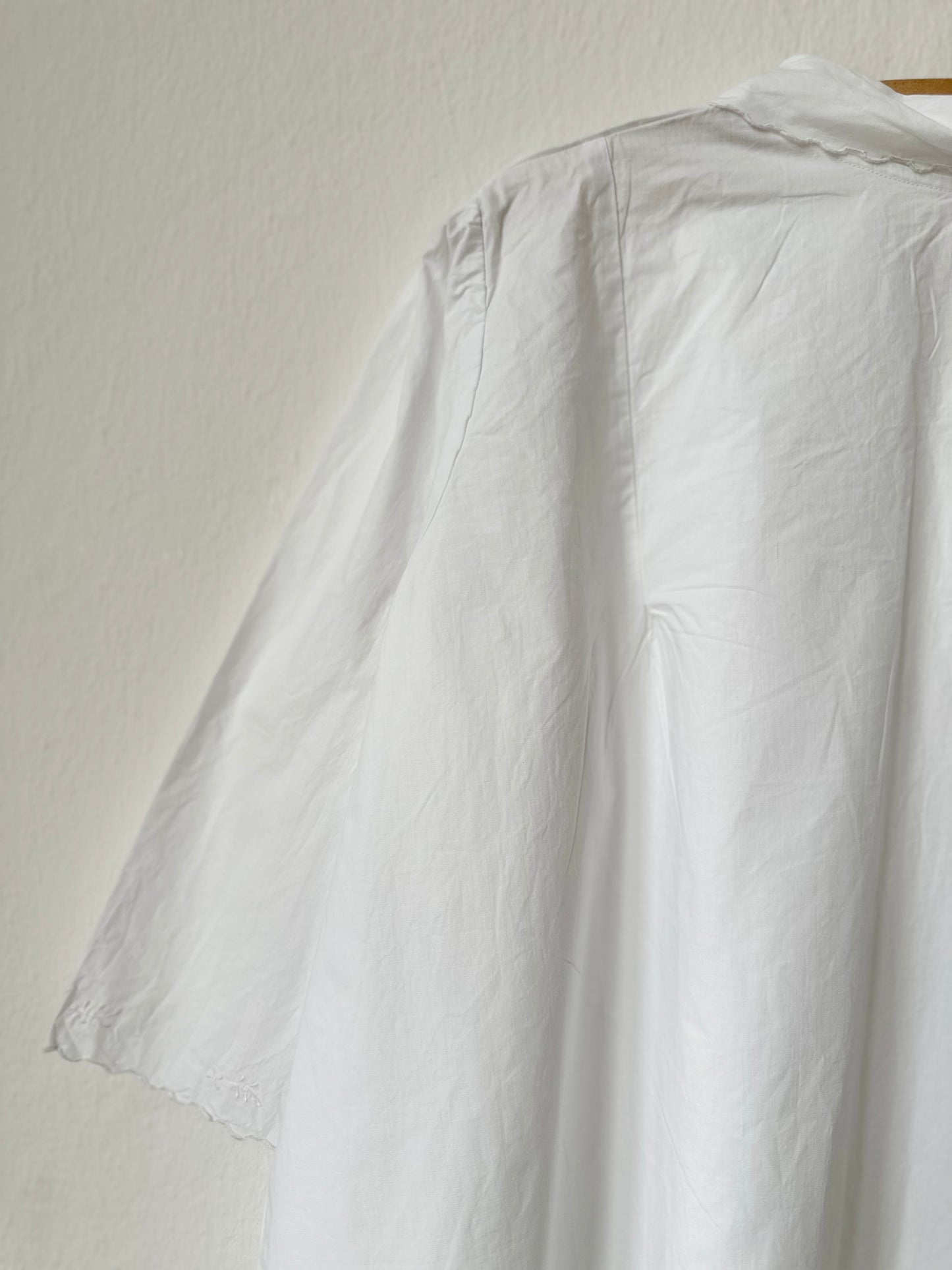 White vintage dress on a hanger against a plain background