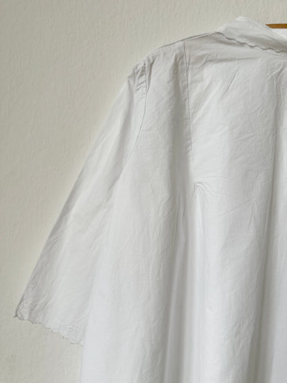 White vintage dress on a hanger against a plain background
