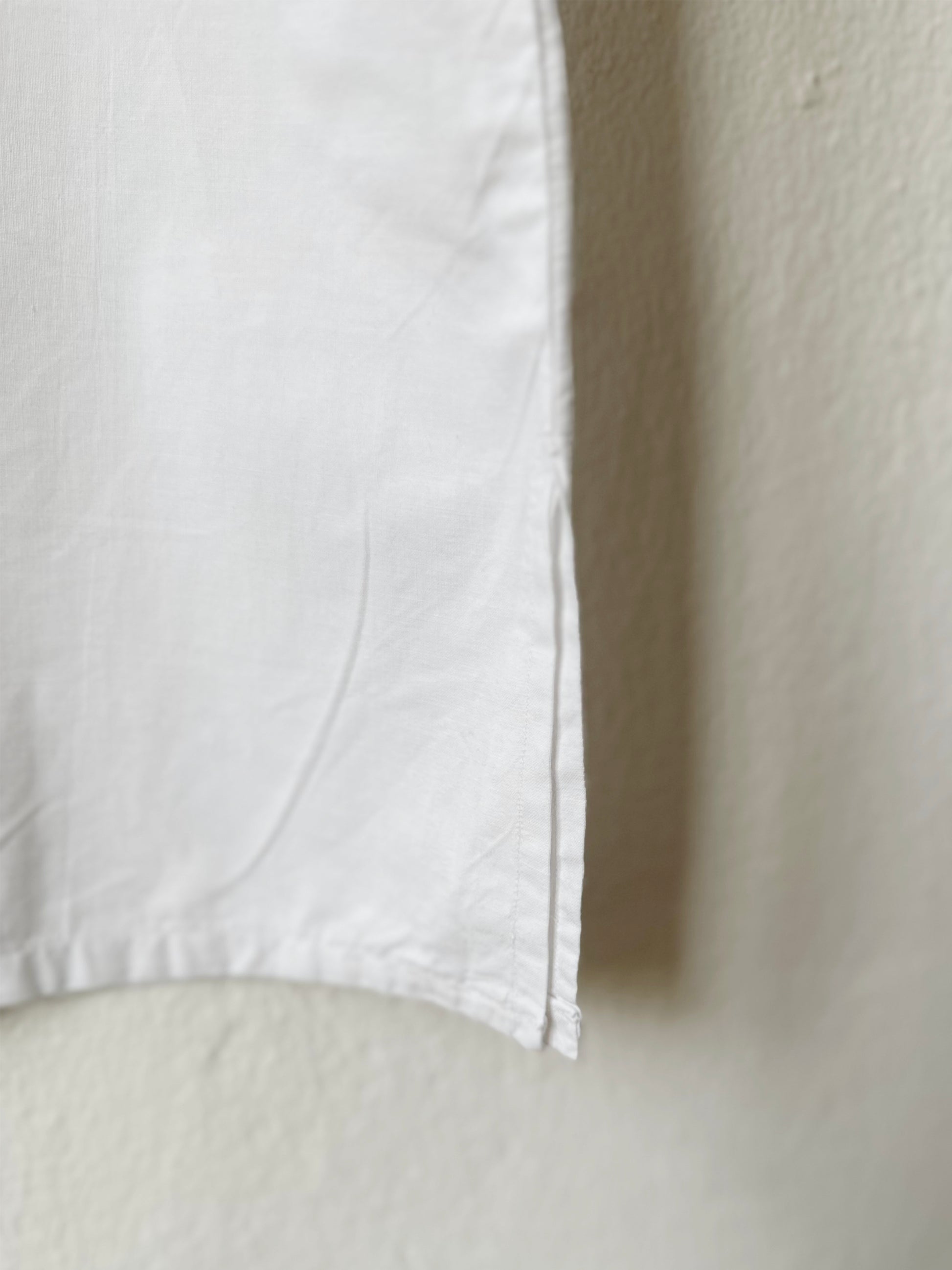 Close-up of a white vintage top with a textured beige background