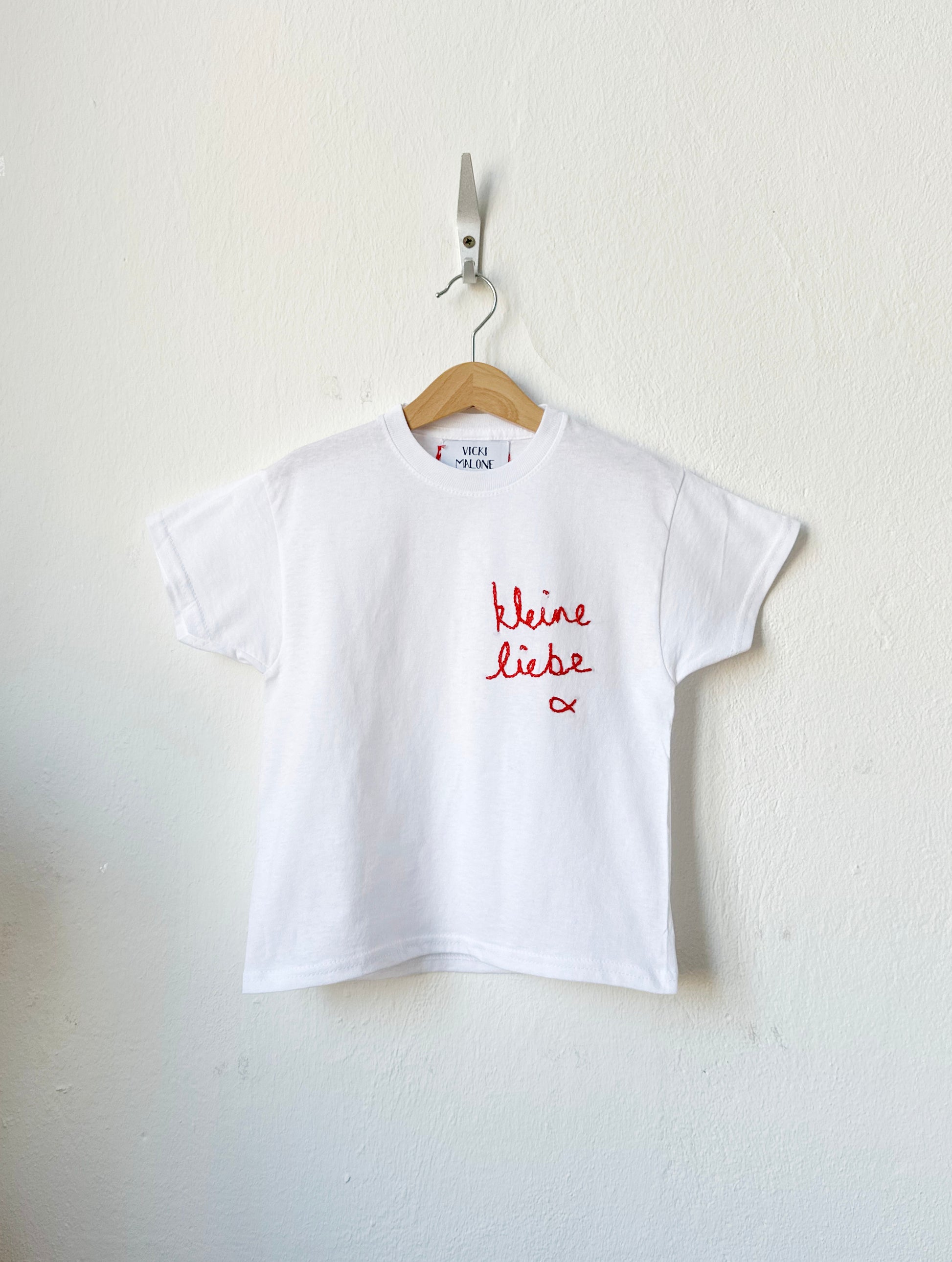 White t-shirt with red text on a hanger against a white background