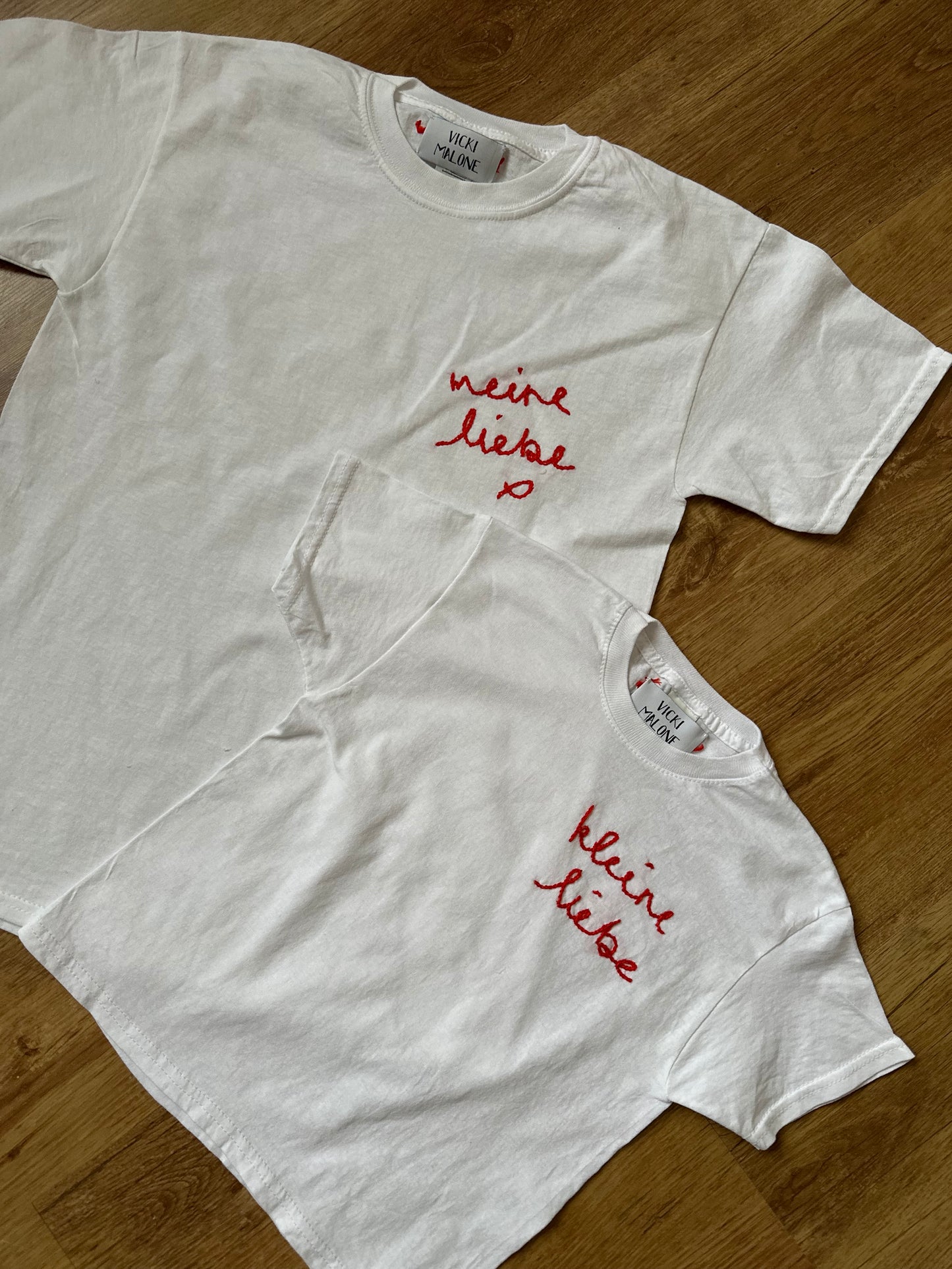 White t-shirts with red text on a wooden surface